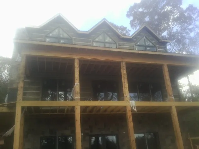 Dormers and porch framing on a large log home under construction — Roof Coating work by our crew in Armstrong Creek
