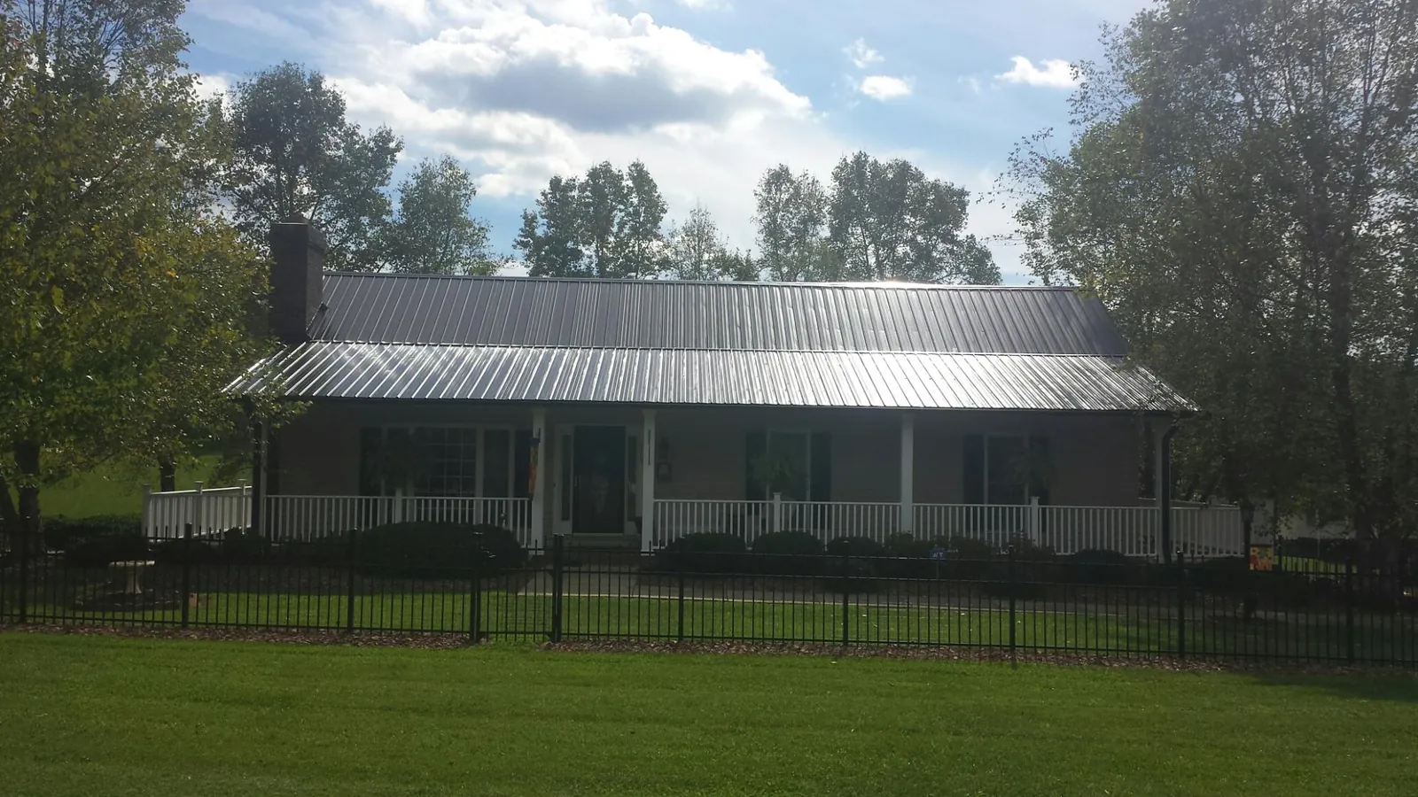 Gray metal roof on a brick ranch with a full width front porch — Gutter Guard Installation work by our crew in Armstrong Creek