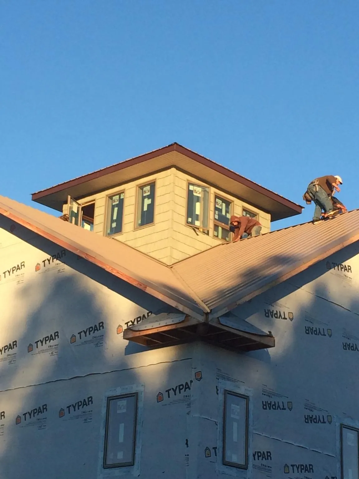 Roofers working around a rooftop cupola on a new metal roof at sunset — Roof Waterproofing in Armstrong Creek by Roofing Brothers